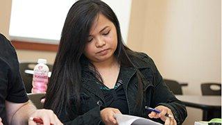 Asian girl flipping papers as she sits in class